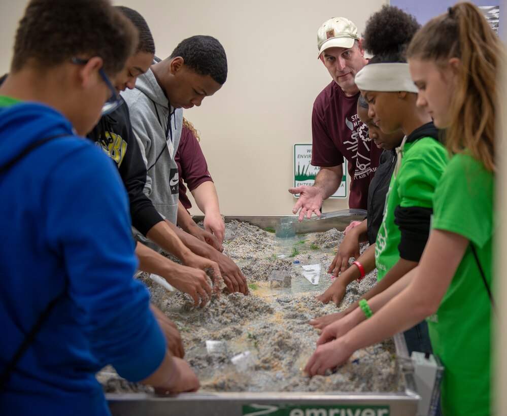 Volunteers explain the effects water has on the environment to local school children at Scott Air Force Base, Ill., March 28, 2019. Each exhibit allowed varying levels of participation for visiting students, often giving a chance for hands-on application of science, technology, engineering, arts, and math topics. (U.S. Air Force photo by Senior Airman Greg Erwin)