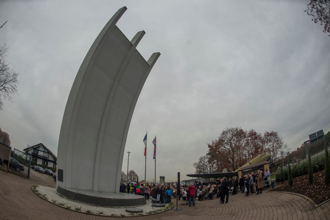 A group stands below a large sculpture.