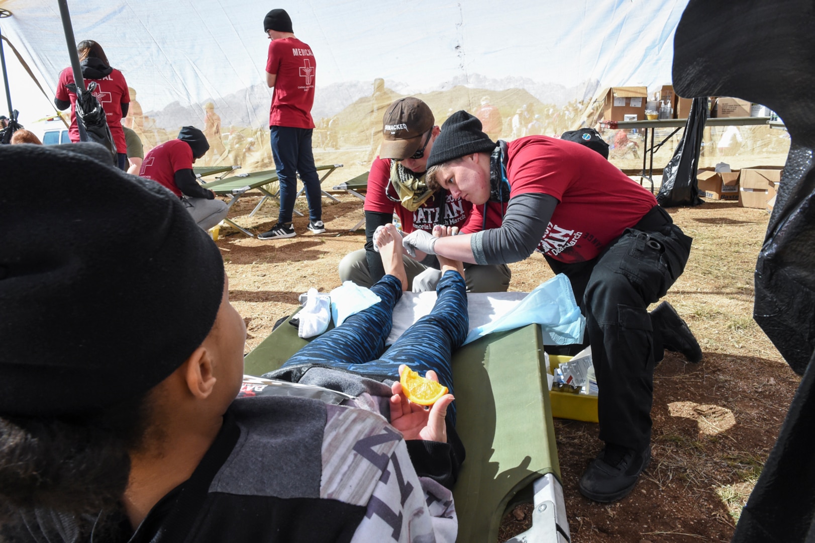 Petty Officer 1st Class Aretha Carmouche receives treatment on her blisters during the 2019 Bataan Memorial Death March, in White Sands, New Mexico, March 17, 2019.
