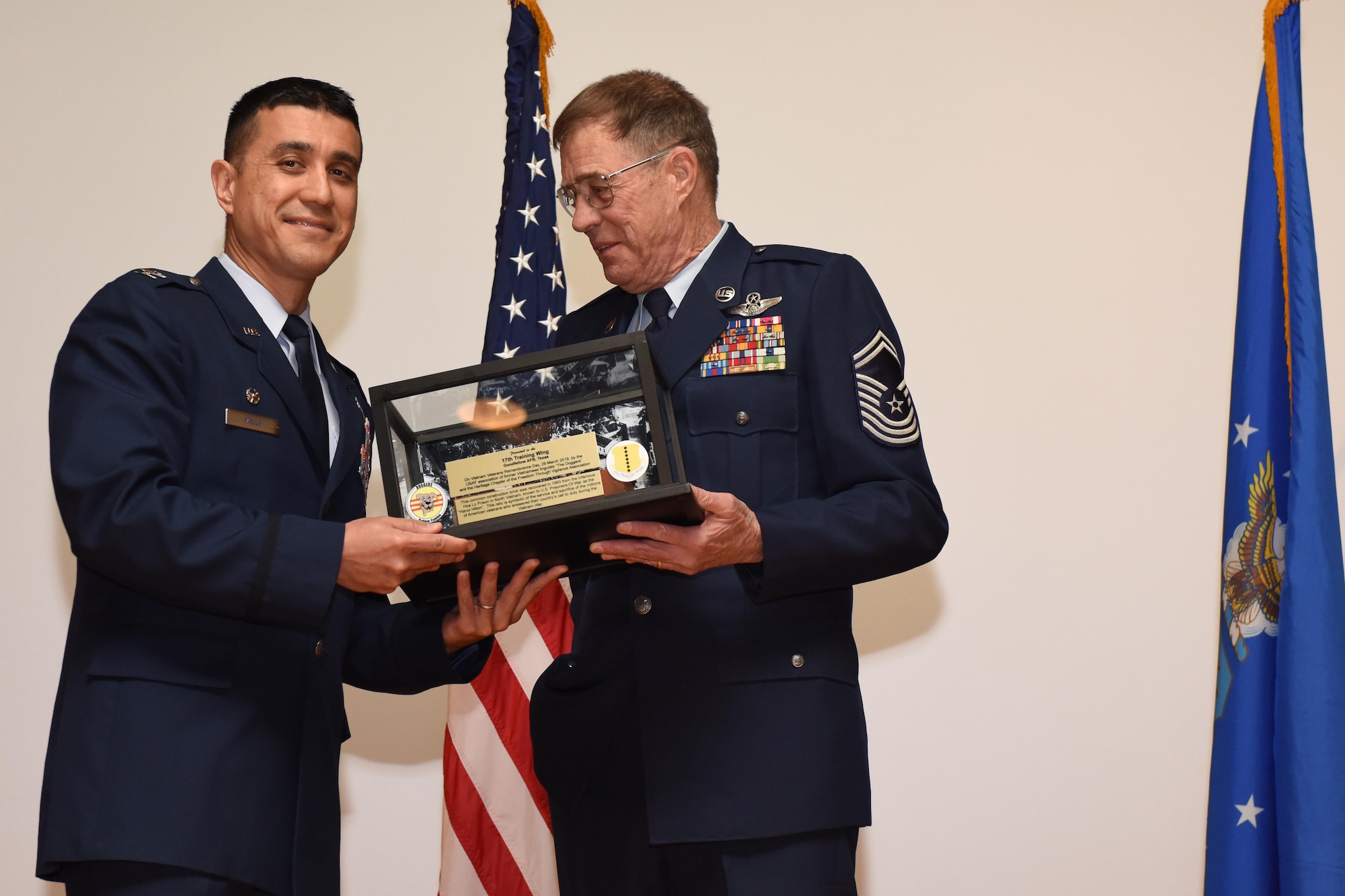 U.S. Air Force Col. Ricky Mills, 17th Training Wing commander, receives a brick from the Hanoi Hilton, presented by retired Chief Master Sgt. Larry Mills at the Base Theater on Goodfellow Air Force Base, Texas, March 29, 2019. The brick was given to the 17th Training Wing by The Heritage Chapter of the Freedom Through Vigilance Association. A symbol of those who answered the call to the Vietnam War, the brick is to never forget those who came before us. (U.S. Air Force photo by Senior Airman Seraiah Hines/Released)