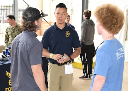 Petty Officer 1st Class Yong Yo (center), a special warfare scout assigned to Navy Recruiting District San Antonio, speaks with attendees about career opportunities in America’s Navy during the 92nd Clyde Littlefield Texas Relays held at the Mike A. Myers Stadium on the campus of the University of Texas in Austin.
