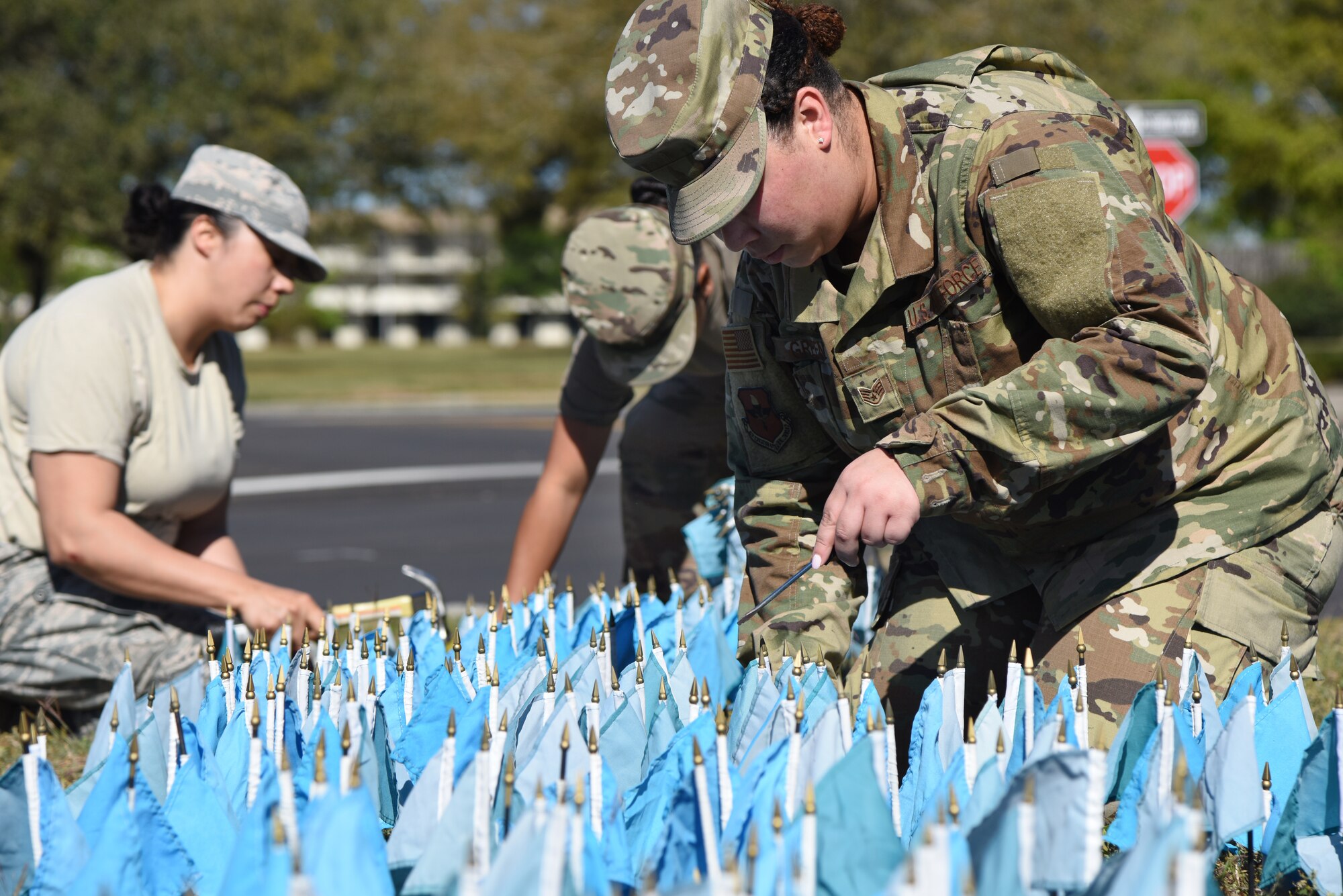 U.S. Air Force Staff Sgt. Cheyenne Green, 81st Training Support Squadron curriculum developer, (right) and Staff Sgts. Julie Minjarez, 85th Engineering Installation Squadron project manager, and Lionyann Maynard, 85th EIS radio frequency transmissions systems technician, place teal colored flags in the ground for Sexual Assault Awareness Month near the Keesler Base Exchange satellite pharmacy on Keesler Air Force Base, Mississippi, April 2, 2019. Each flag represents five Department of Defense members who reported being sexually assaulted in fiscal year 2017. The 1,354 flag display will be moved to several locations around the base throughout the month. Keesler's Sexual Assault Prevention and Response office provides sexual assault response coordinators and victim advocates to assist victims and survivors of sexual assault. (U.S. Air Force photo by Kemberly Groue)