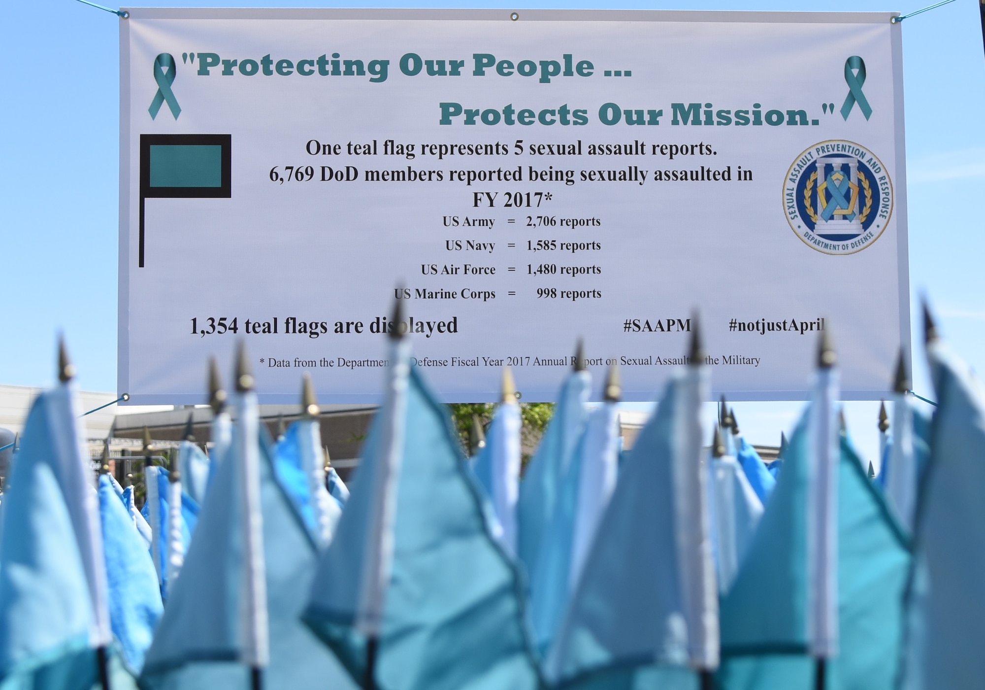 A Sexual Assault Awareness Month banner is displayed near the Keesler Base Exchange satellite pharmacy on Keesler Air Force Base, Mississippi, April 2, 2019. Each flag represents five Department of Defense members who reported being sexually assaulted in fiscal year 2017. The 1,354 flag display will be moved to several locations around the base throughout the month. Keesler's Sexual Assault Prevention and Response office provides sexual assault response coordinators and victim advocates to assist victims and survivors of sexual assault. (U.S. Air Force photo by Kemberly Groue)