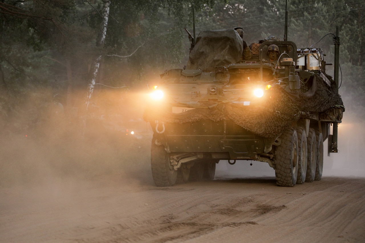 An infantry carrier vehicle moves on a dusty road.