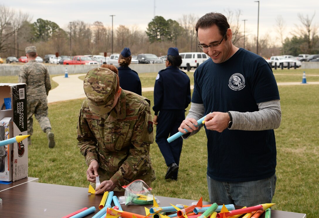 Senior Master Sgt. Amanda Pelletier, 375th Air Mobility Wing superintendent, and Kamron Ahmad, 375th AMW Judge Advocate’s Office attorney advisor, tape together construction paper rockets during STEAM Day at Scott Air Force Base, Ill., March 28, 2019. The rockets were used as part of a demonstration to help students understand more about aerodynamics. (U.S. Air Force photo by Airman 1st Class Miranda Simpson)