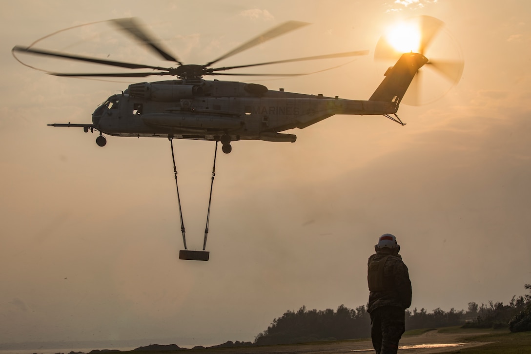 U.S. Marine Corps Sgt. Christian R. Smith observes a CH-53E Super Stallion helicopter lift a training block on Landing Zone Swan, Okinawa, Japan March 29, 2019. Helicopter Support Team operations are conducted to train landing support specialists and pilots for transferring heavy equipment and supplies using helicopters. Smith, a landing support specialist with Headquarters and Service Company, Combat Logistics Battalion 4, Combat Logistics Regiment 3, 3rd Marine Logistics Group, is a native of Gainesville, Georgia.