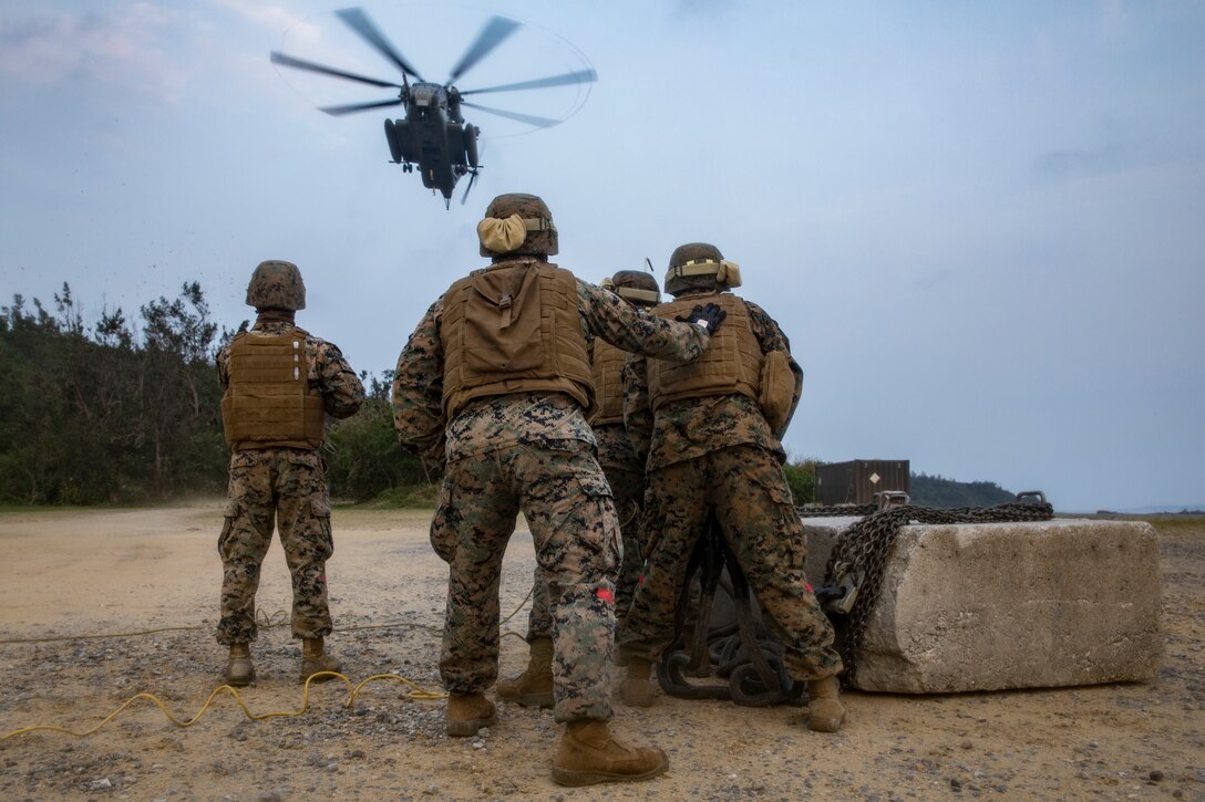 U.S. Marines Corps landing support specialists with Headquarters and Service Company, Combat Logistics Battalion 4, Combat Logistics Regiment 3, 3rd Marine Logistics Group, prepare a training block to be lifted by a CH-53E Super Stallion helicopter on Landing Zone Swan, Okinawa, Japan March 29, 2019. Helicopter support team operations are conducted to train landing support specialists and pilots for transferring heavy equipment and supplies using helicopters.