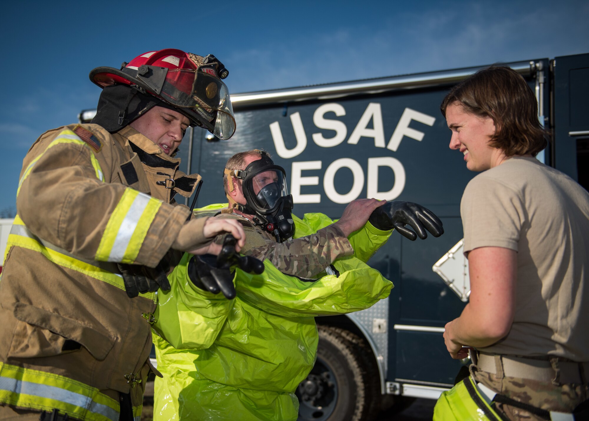 A U.S. Air Force Airman from the 633rd Civil Engineer Squadron fire department helps Airmen from the 633rd CES explosive ordnance disposal gear up during an active chemical, biological, radiological and nuclear (CBRN) response training at Joint Base Langley-Eustis, Virginia, March 29, 2019.