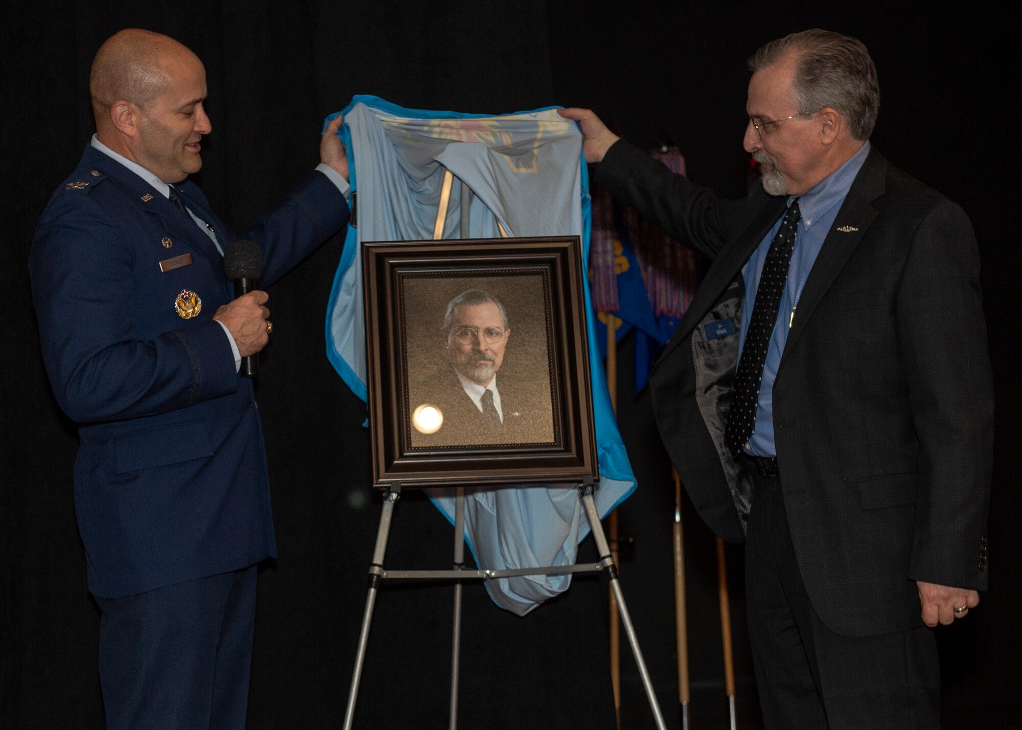 U.S. Air Force Col. Eric Carney, 97th Air Mobility Wing commander, and Jim Gover, president of Lending and Corporate Security Officer at NBC Bank in Altus, unveil Gover’s portrait during the friends of Altus Induction Ceremony, March 29, 2019, at Altus Air Force Base, Okla. Gover previously served in the U.S. Navy and remains an avid supporter of the armed services. (U.S. Air Force Photo by Senior Airman Jackson N. Haddon)