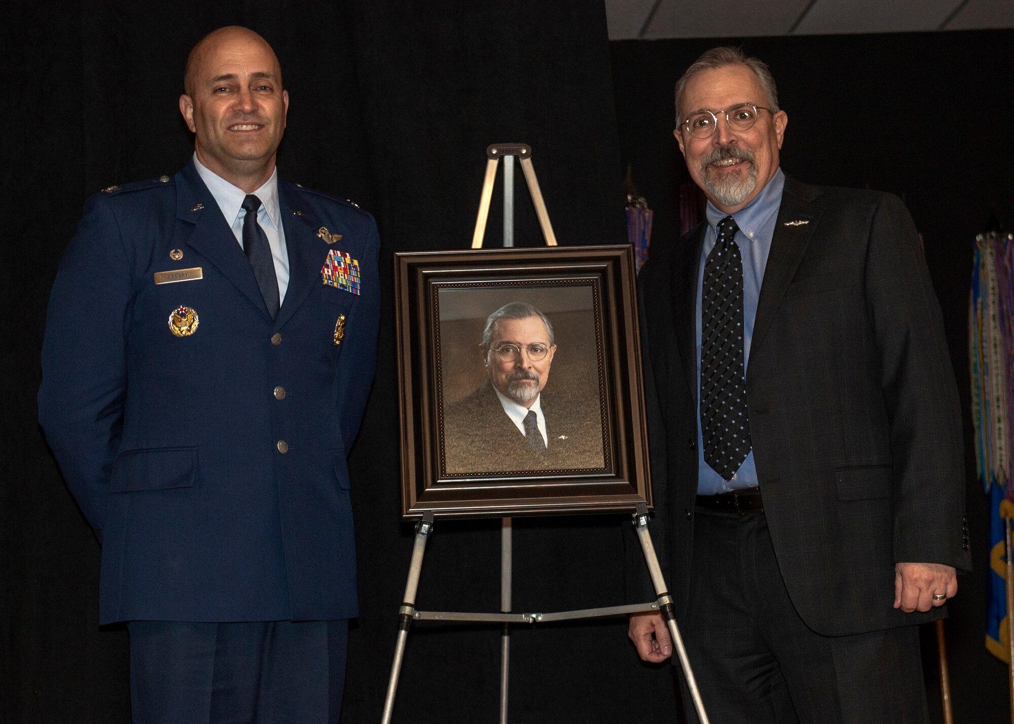 U.S. Air Force Col. Eric Carney, 97th Air Mobility Wing commander, and Jim Gover, president of Lending and Corporate Security Officer at NBC Bank in Altus, stand by his portrait during the friends of Altus Induction Ceremony, March 29, 2019, at Altus Air Force Base, Okla. The portrait will be hung in the Wing command building along with the other Friends of Altus. (U.S. Air Force Photo by Senior Airman Jackson N. Haddon Jackson N. Haddon)