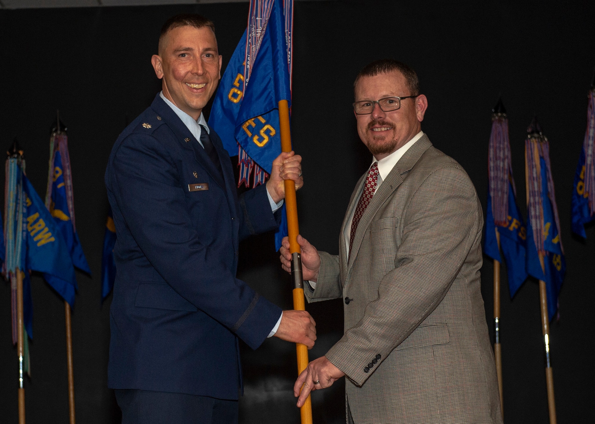 U.S. Air Force Lt. Col. Steven Thomas, 97th Civil Engineer Squadron commander, hands the 97th CES guidon to Mr. Kevin Marple, Johnny Roberts Motors director, during the Honorary Commanders Induction, March 29, 2019, at Altus Air Force Base, Okla. Inductees were called to the stage to meet with their commanders and receive a 97th Air Mobility Wing pin as a symbol of recognition. (U.S. Air Force Photo by Senior Airman Jackson N. Haddon)