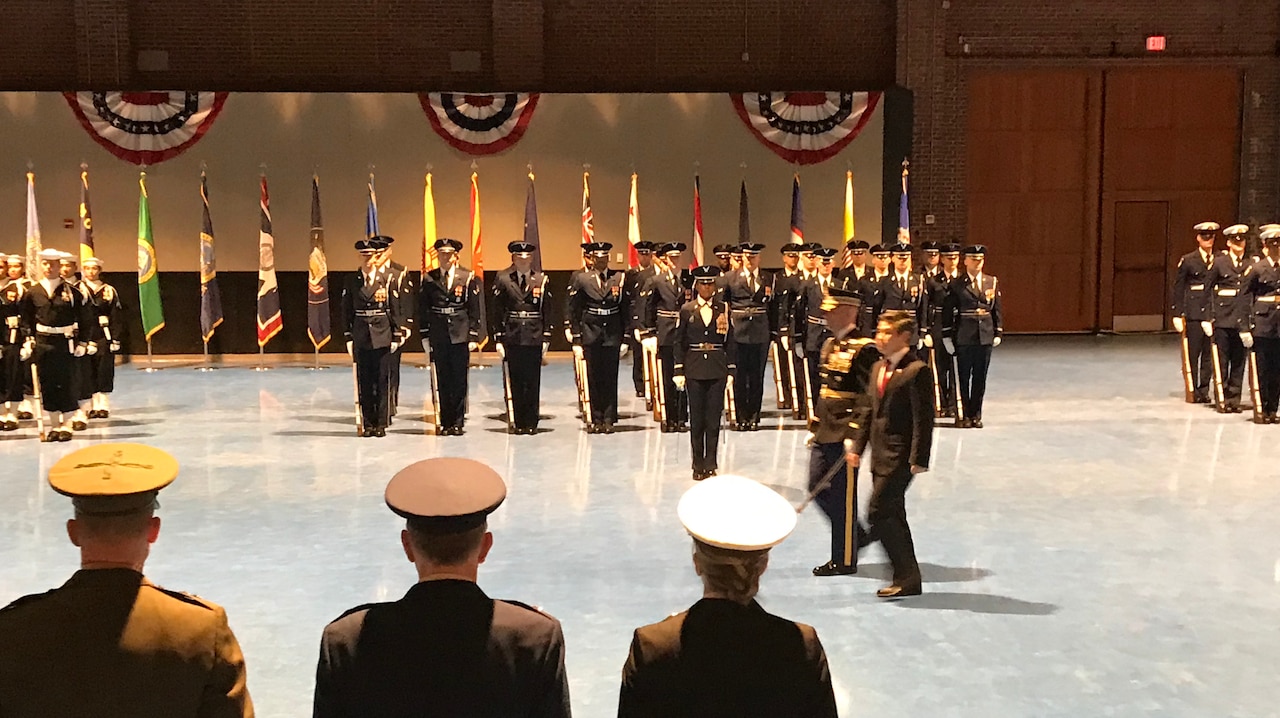 Military men march before other troops.