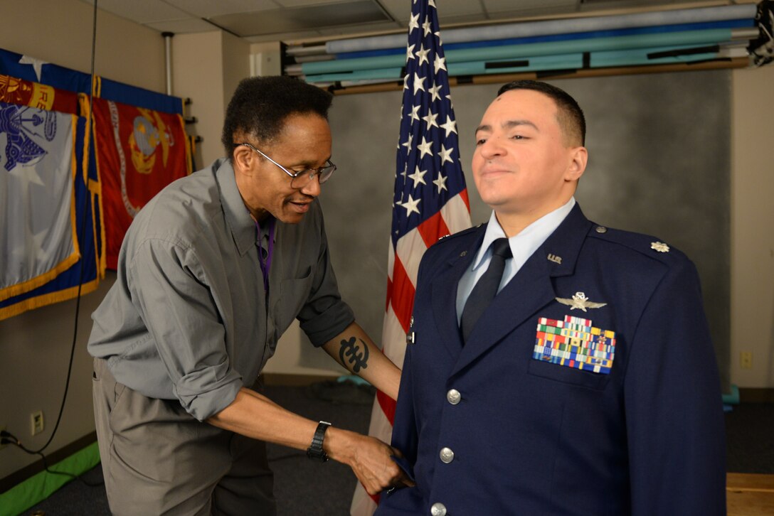 Dana Heard, 55th Wing Public Affairs photojournalist, adjusts the uniform of Lt. Col. Nelson Caraballo, 55th Strategic Communications Squadron director of operations, April 3, 2019, on Offutt Air Force Base, Nebraska. Heard is the primary photographer in the photo studio. (U.S. Air Force photo by Tech. Sgt. Rachelle Blake)