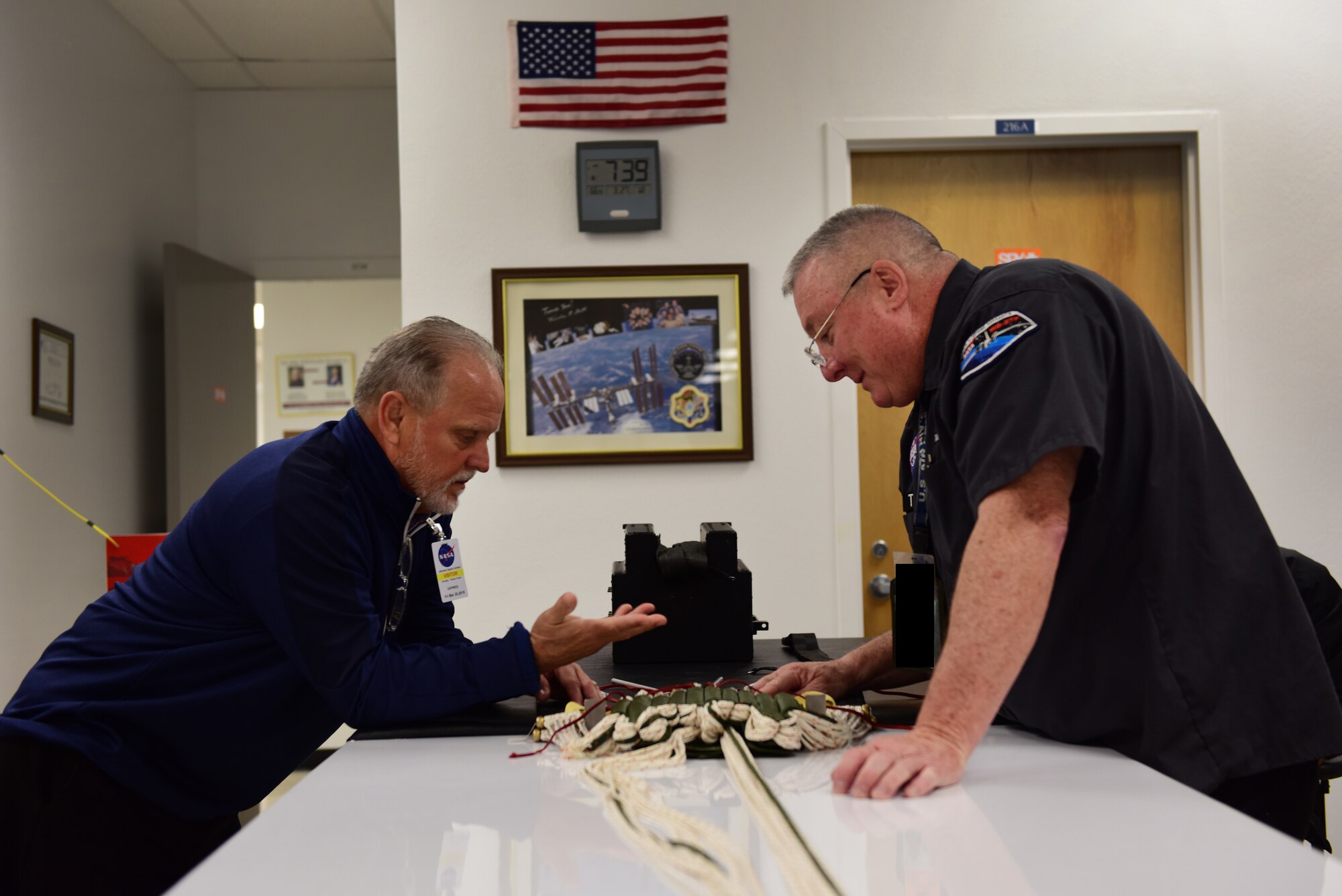 Tommy Sondag, 47th Operations Support Squadron aircrew flight equipment parachute technician, and Troy Stewart, a personal equipment technician contractor for NASA Aircraft Operations, discuss the process of stowing parachute lines at Ellington Airport, Texas, March 27, 2019. Sondag visited NASA's Aircraft Operations T-38 life support to assist in the newly revamped T-38 parachute packing procedures. During his visit, he was given a tour of the NASA facilities in the area. (U.S. Air Force photo by Senior Airman Benjamin N. Valmoja)