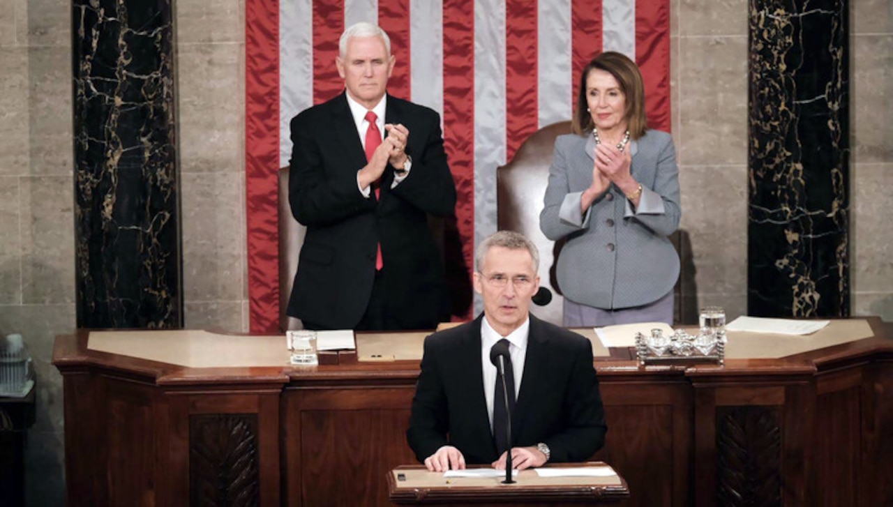 A man speaks as a man and a woman clap behind him.