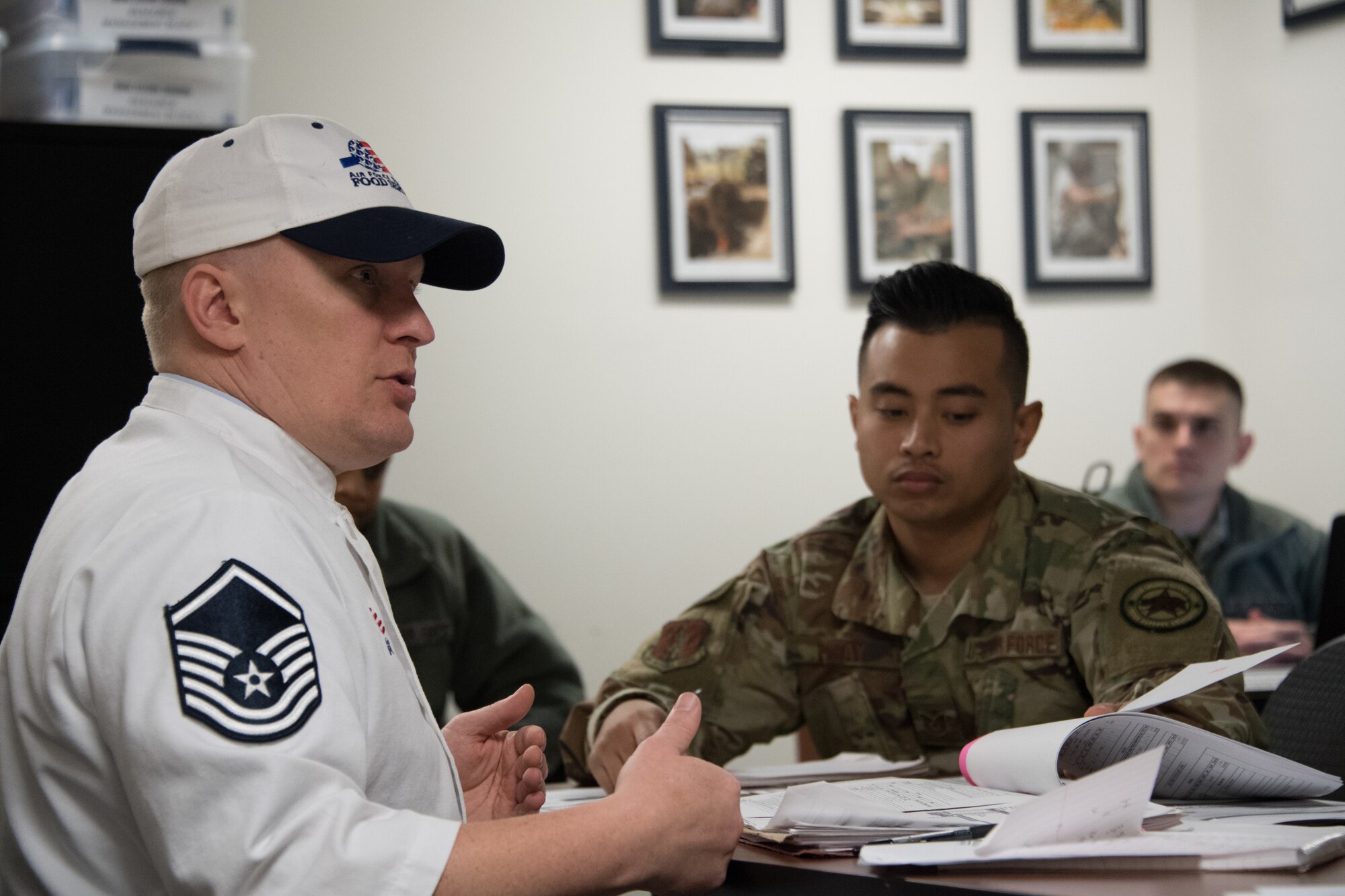 U.S. Air National Guardsman Master Sgt. John Williams an evaluator reviews administrative paperwork with Tech. Sgt. Derrick Viray and other U.S. Air National Guardsman from the 146th Airlift Wing Services Flight Channel Islands Air National Guard Station, Port Hueneme, Calif., Mar. 9, 2019. The 146th Airlift Wing was selected out of 70 other wings for evaluation of kitchen operations for the possibility to win the Kenneth Disney award sponsored by the National Restaurant Association, the Culinary Institute of America and various hospitality industry sponsors for outstanding Air National Guard facilities with best dining operations nationally.  (U.S. Air National Guard photo by Tech. Sgt. Nieko Carzis.)