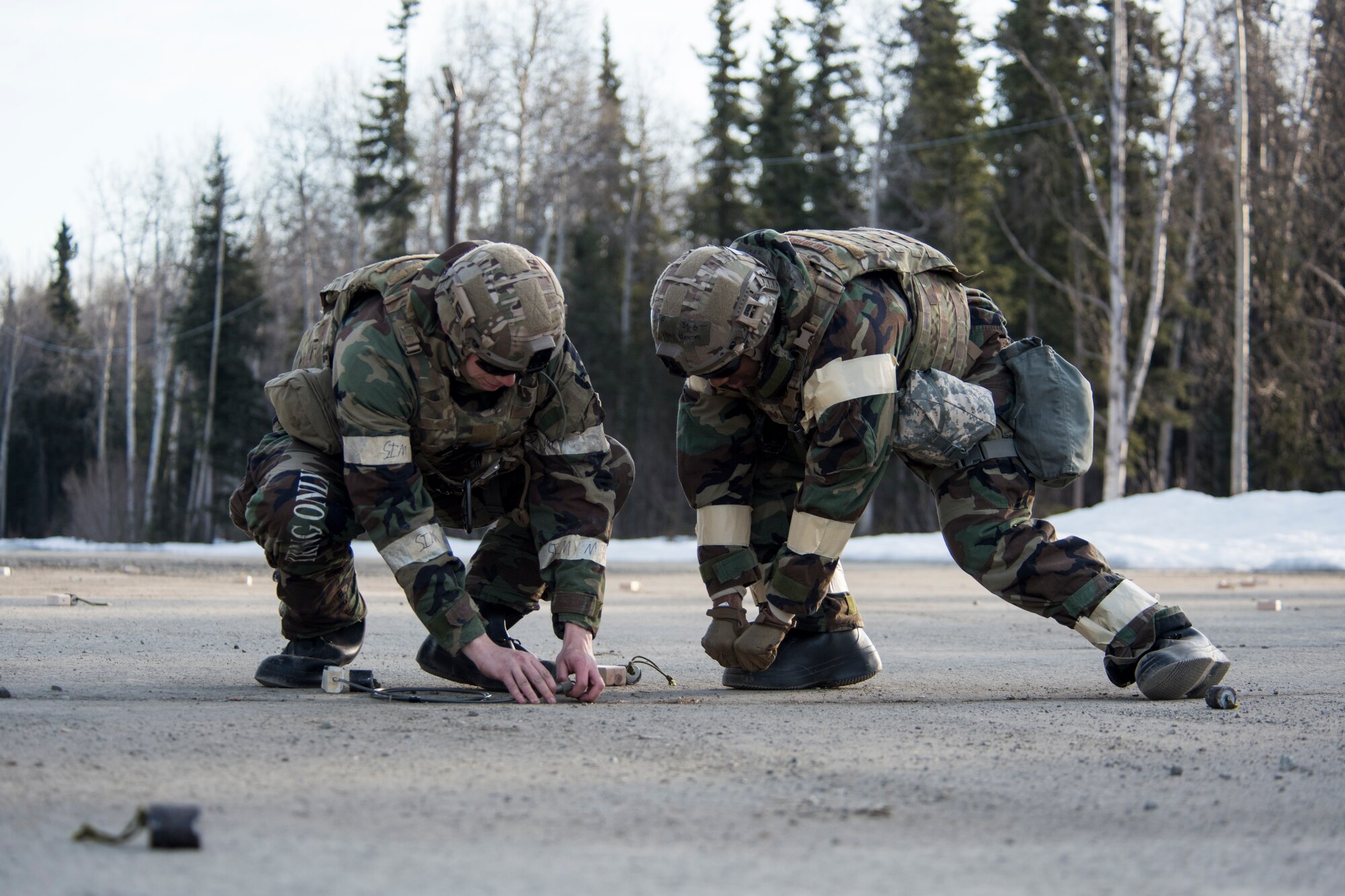 Senior Airmen Joshua Harris and Dillan Owen, 673d Civil Engineer Squadron Explosive Ordnance Disposal journeymen, conduct rapid clearing of submunitions on an airfield in a simulated chemical environment during Polar Force 19-4 at Joint Base Elmendorf-Richardson, Alaska, April 2, 2019. Polar Force is a two-week exercise designed to test JBER’s mission readiness and strengthen and develop the skills service members require when facing adverse situations.