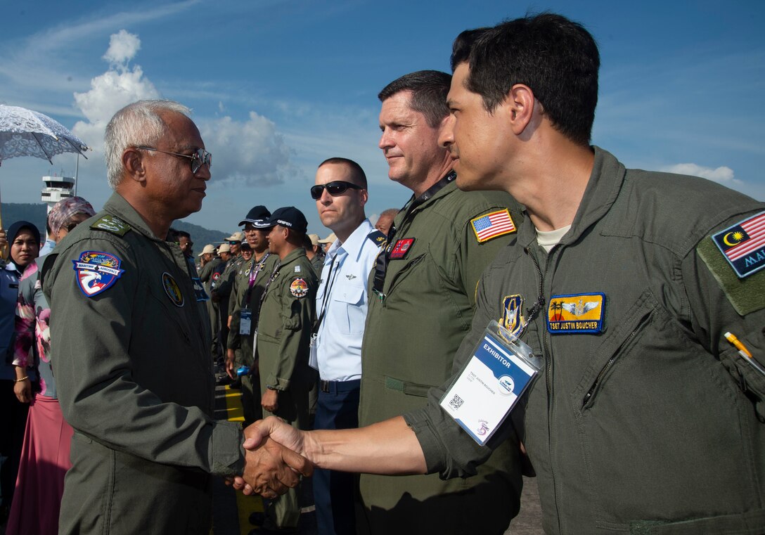 Malaysian Gen. Tan Sri Affendi Buang, Royal Malaysian Air Force chief, shakes hands with U.S. Air Force Tech. Sgt. Justin Boucher, a C-17 Globemaster III loadmaster, assigned to the 452nd Air Mobility Wing, March Air Force Base, Calif., speaks to visitors during the Langkawi International Maritime and Aerospace Exhibition 2019 in Padang Mat Sirat, Malaysia, March 29, 2019.