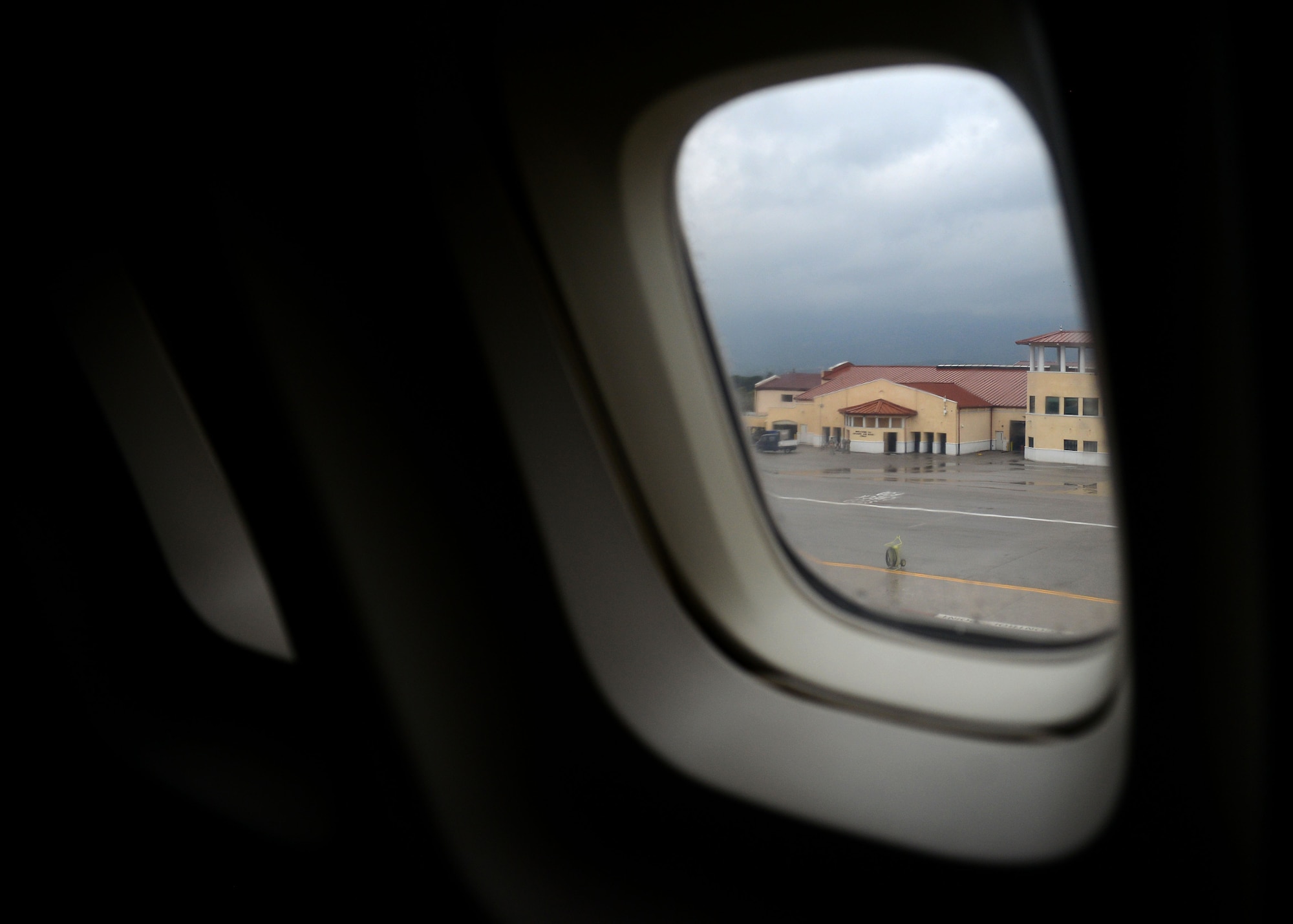An aircraft window frames the view of the Aviano Passenger Terminal at Aviano Air Base, Italy, April 4, 2019. The terminal, ran by members of the 724th Air Mobility Squadron, recently reactivated the Patriot Express service, allowing passengers to fly directly to and from Aviano AB. (U.S. Air Force photo by Staff Sgt. Rebeccah Woodrow)