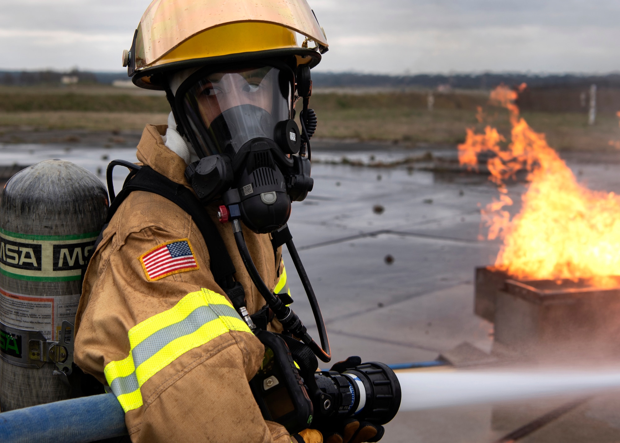 Omar Moylan, a senior at Spangdahlem High School, looks back to his partner for guidance during a live-fire simulated aircraft burn exercise at Spangdahlem Air Base, Germany, March 26, 2019. The exercise was Moylan's first experience extinguishing a live fire. He has been training with the 52nd Civil Engineer Squadron Fire Department for two months and plans to continue until he graduates. (U.S. Air Force photo by Airman 1st Class Valerie Seelye)