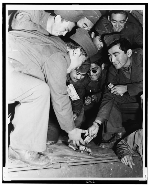 Several soldiers play dominoes on the bed of a truck.