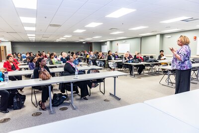 Woman speaks to a full classroom