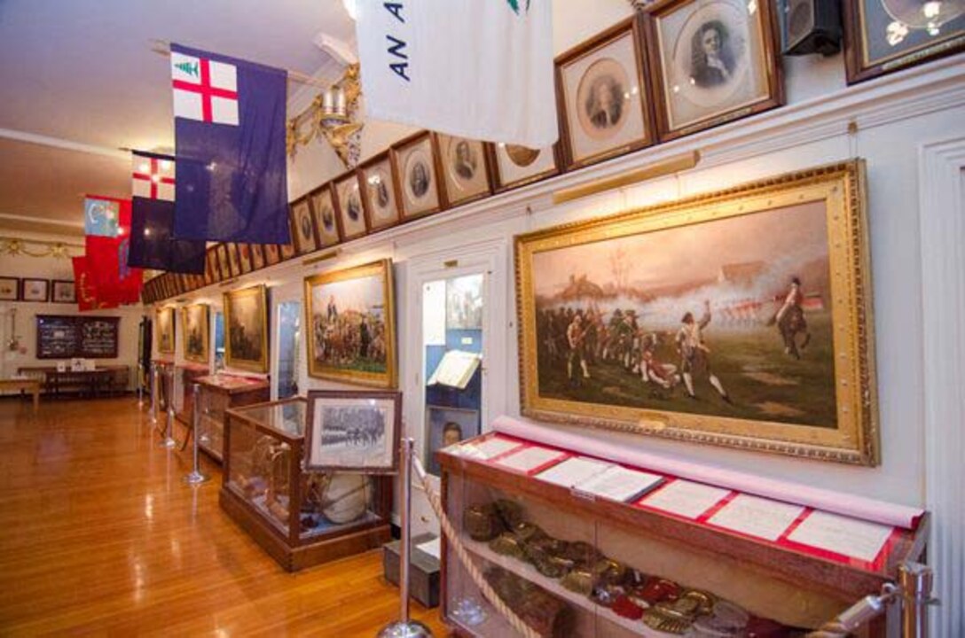 A room in a museum filled with paintings and artifacts in glass cases.