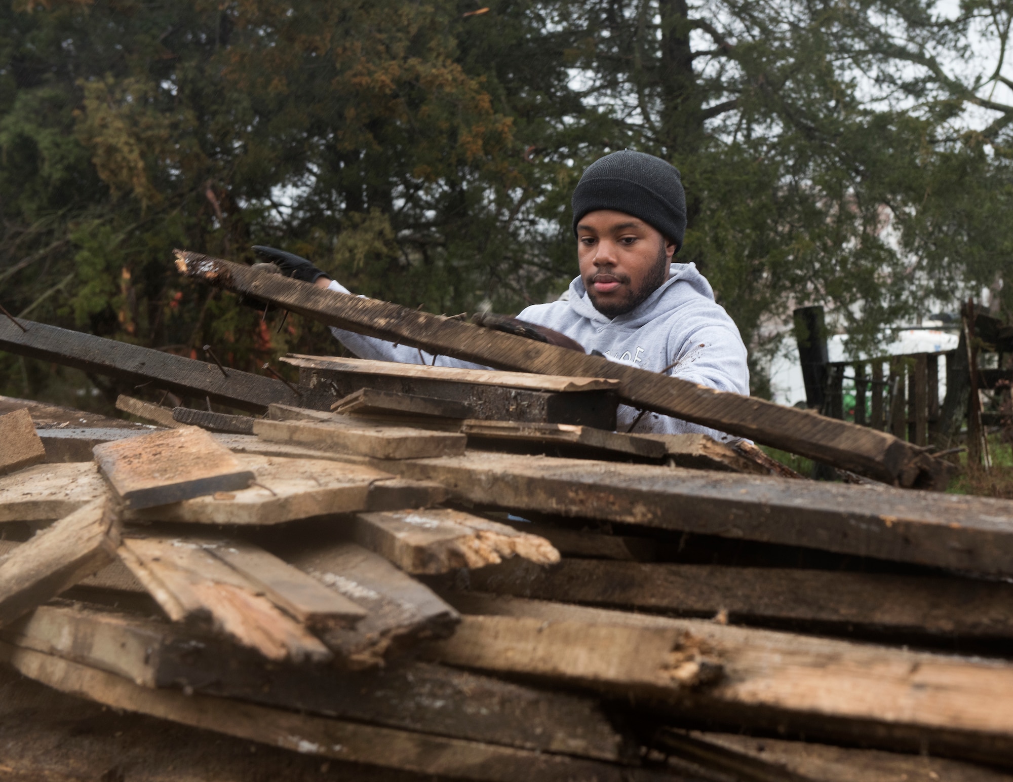 Airman 1st Class Noah Singleton, a security forces response member assigned to the 509th Security Forces Squadron at Whiteman Air Force Base, Missouri, stacks scrap wood on March 30, 2019, on a farm in Knob Noster, Missouri.