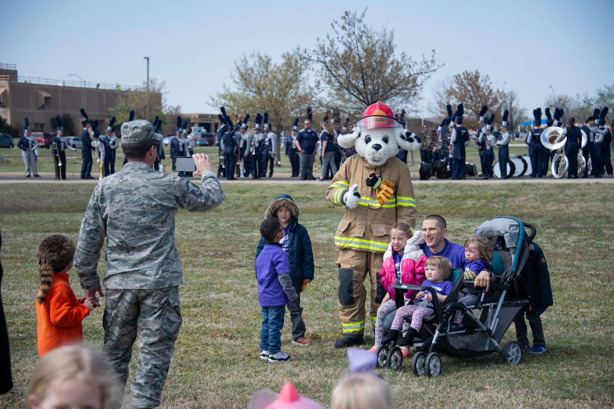 A family poses with Sparky the Fire Dog, April 1, 2019, at Altus Air Force Base, Okla. Members of the 97th Air Mobility Wing wore purple to recognize the start of the Month of the Military Child. (U.S. Air Force photo by Senior Airman Cody Dowell)