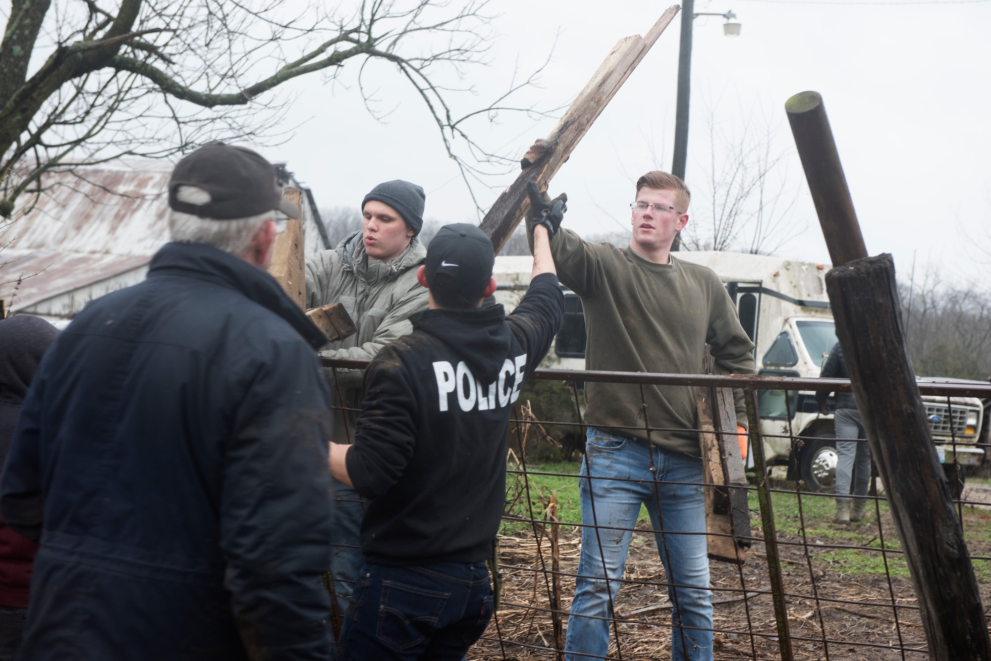 Airman 1st Class Mitchell Beauchamp hands a piece of wood to Airman 1st Class Miguel Tapia on a farm in Knob Noster, Missouri, on March 30, 2019.