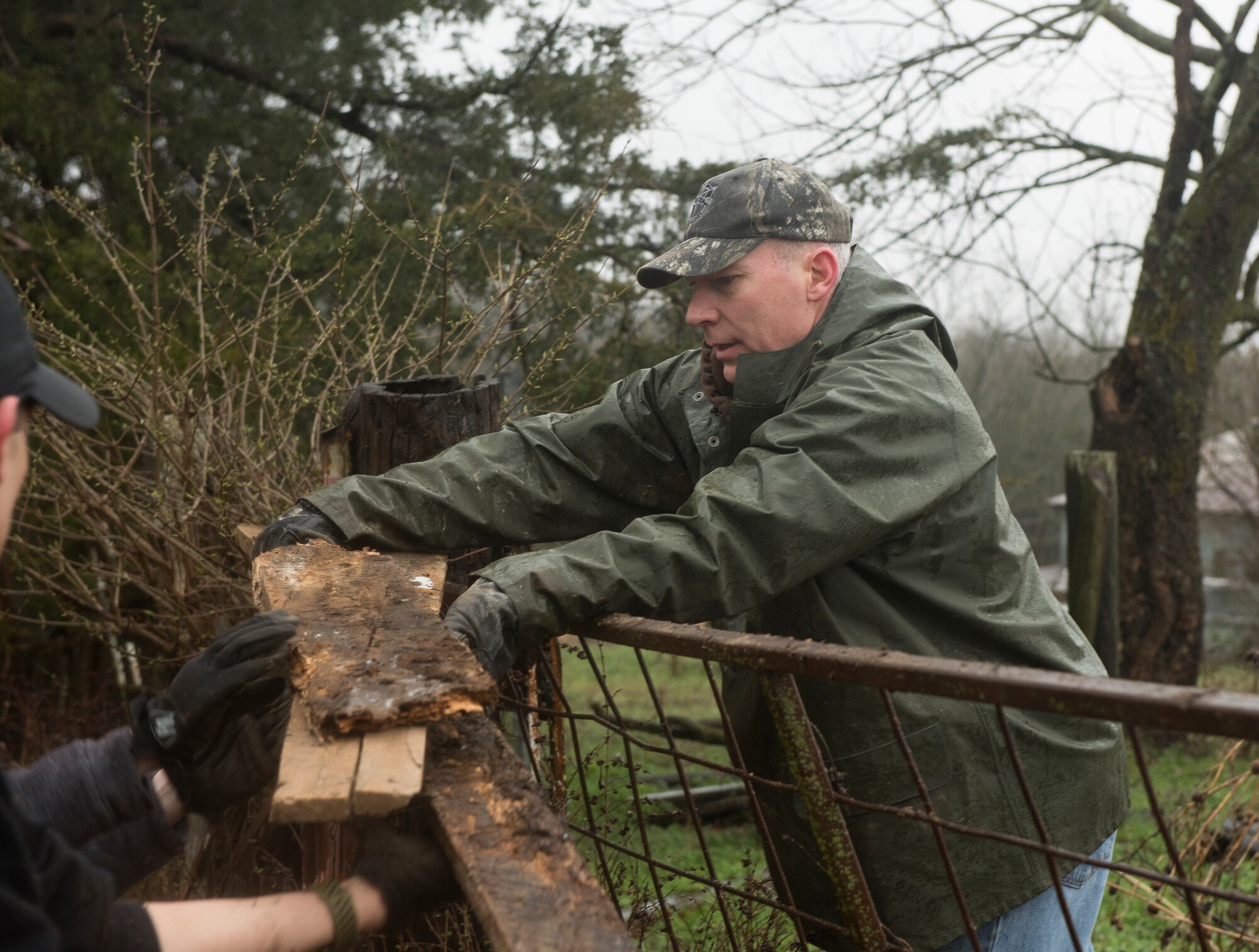 Air Force Col. Christopher Callis, 509th Mission Support Group commander, hands scrap wood to another volunteer on March 30, 2019, on a farm in Knob Noster, Missouri.