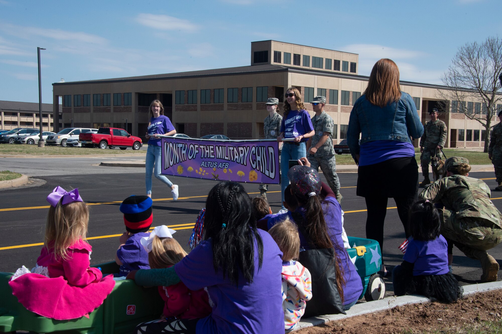 Members of the 97th Air Mobility Wing youth center watch the front of the Month of the Military Child parade, April 1, 2019, at Altus Air Force Base, Okla. After the parade passed by, the members joined in to walk with the rest of the agencies supporting the event. (U.S. Air Force photo by Senior Airman Cody Dowell)