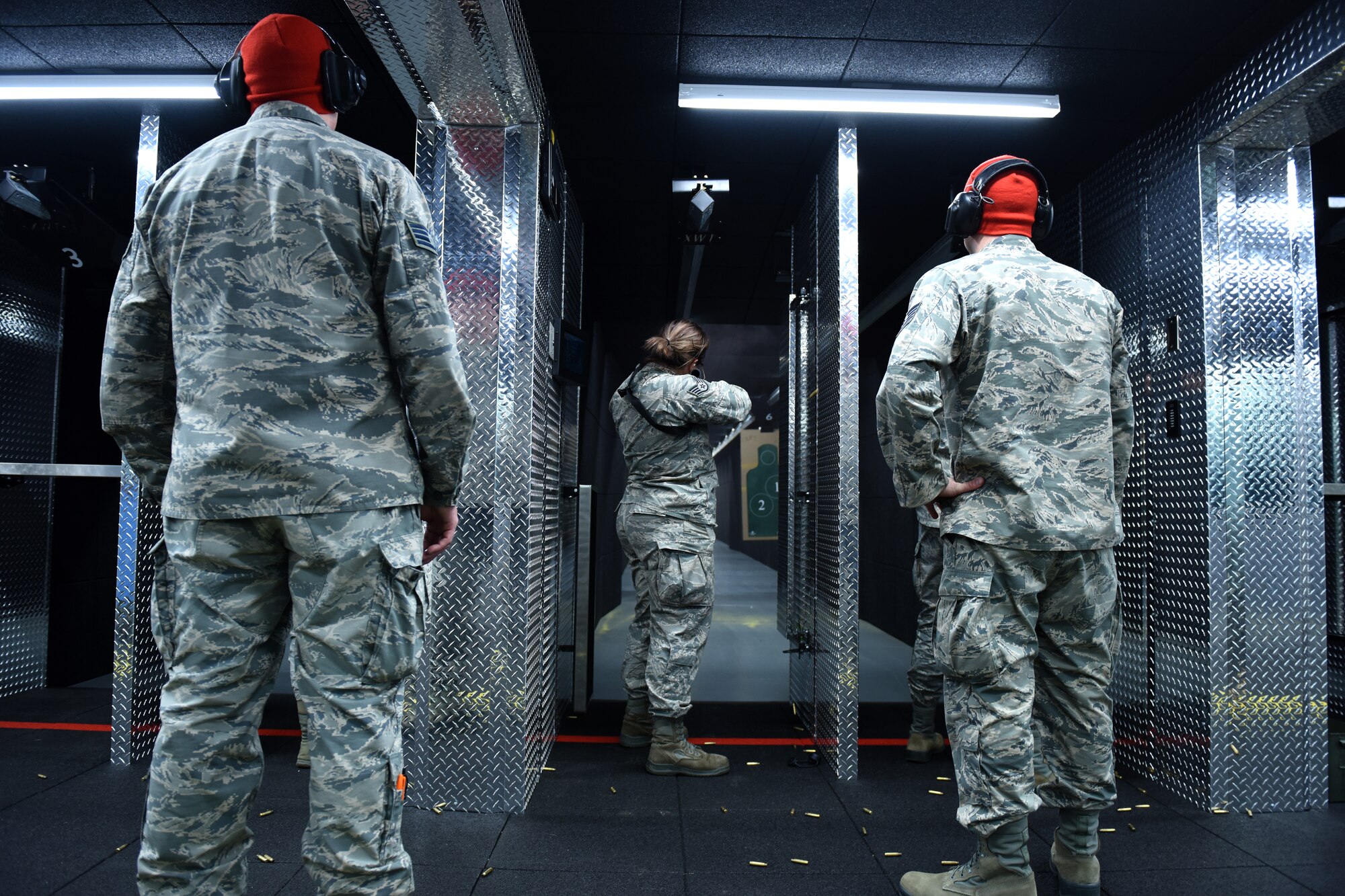 Combat arms training maintenance instructors assigned to the 180th Fighter Wing security forces squadron, Ohio Air National Guard observe as an Airman shoot during the first weapons qualification class in the new Modular Small Arms Range in Swanton, Ohio, Nov. 30, 2018. The high-tech facility is climate-controlled, has high efficiency air handlers, bullet traps and multiple simulation options that promotes safety, while providing scenario-based shooting situations for personnel to train and meet readiness requirements. (Air National Guard Photo by Senior Airman Hope Geiger)