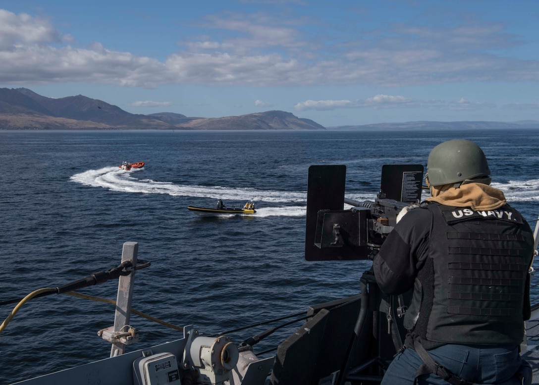 A sailors simulates firing a machine gun.