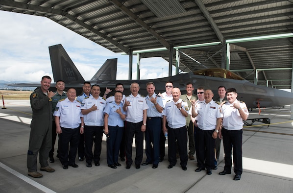 Airmen from the Mongolian Air Force Command and Pacific Air Forces take a group photo in front of a Hawaii Air National Guard F-22 Raptor during a tour around Joint Base Pearl Harbor-Hickam, Hawaii, March 26, 2019.