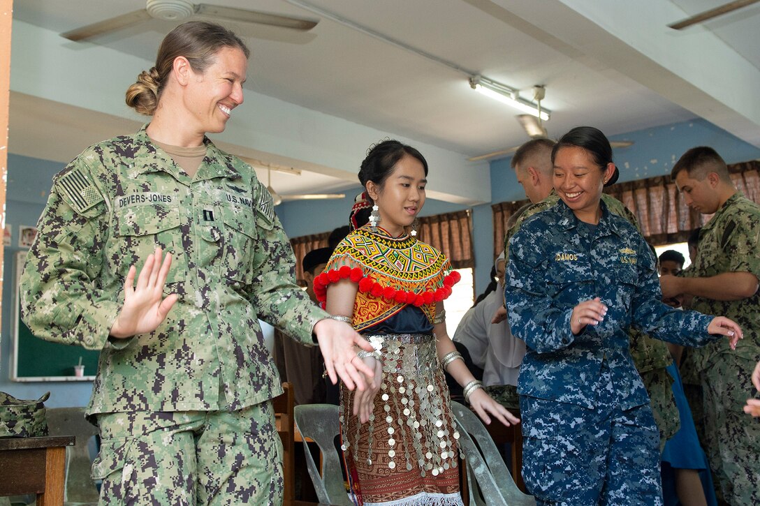 Sailors dance with a student.