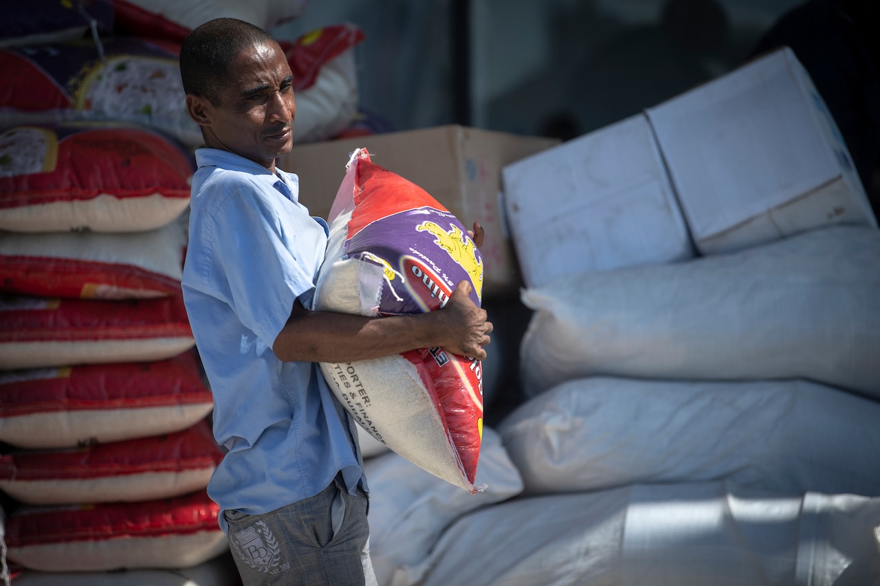 An aid worker carries a bag of food