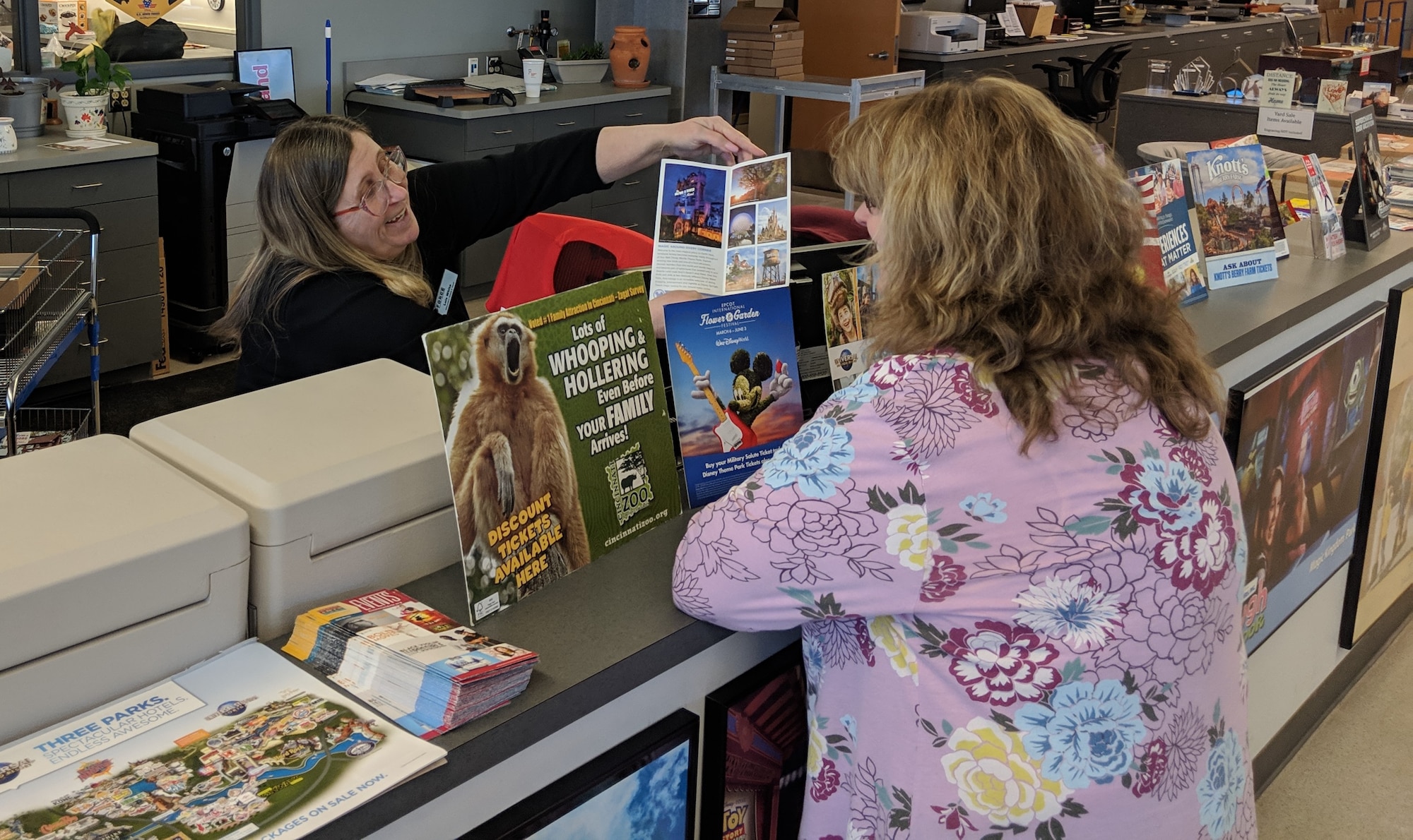 Recreation Specialist, Lois White, shows a customer a Disney brochure. The ITT office offers various discount tickets to parks and events both local and nation-wide. (U.S. Air Force photo/Loren Deer)