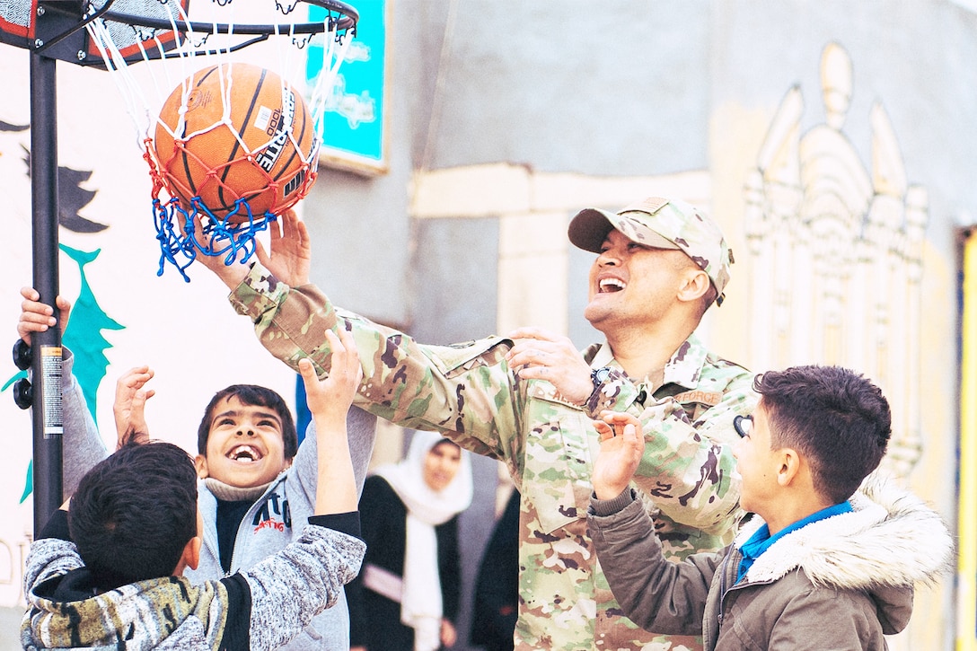 An Airman plays basketball with children.