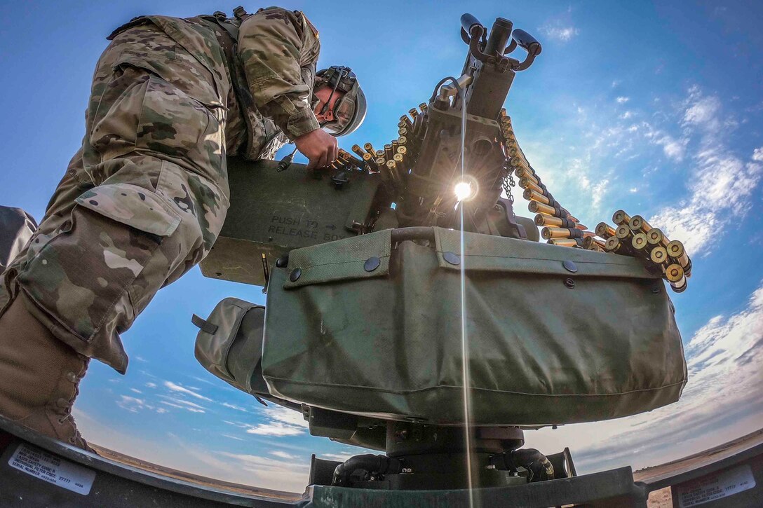 A soldier loads ammunition into a large gun.