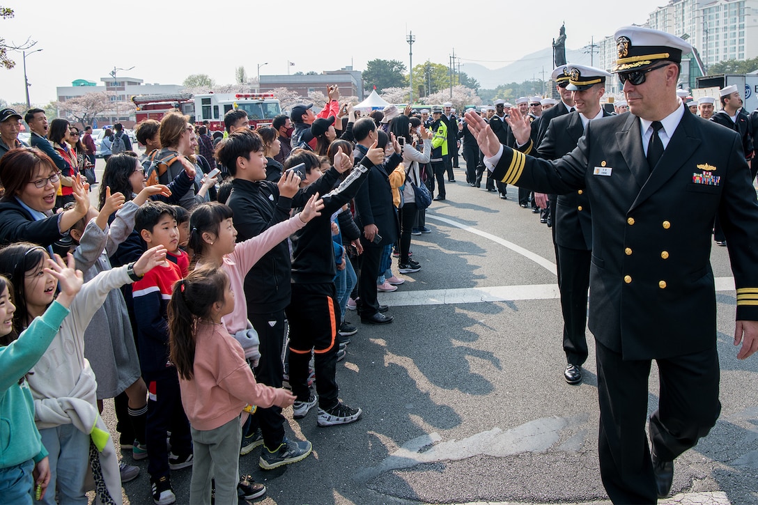 A sailor waves to children.