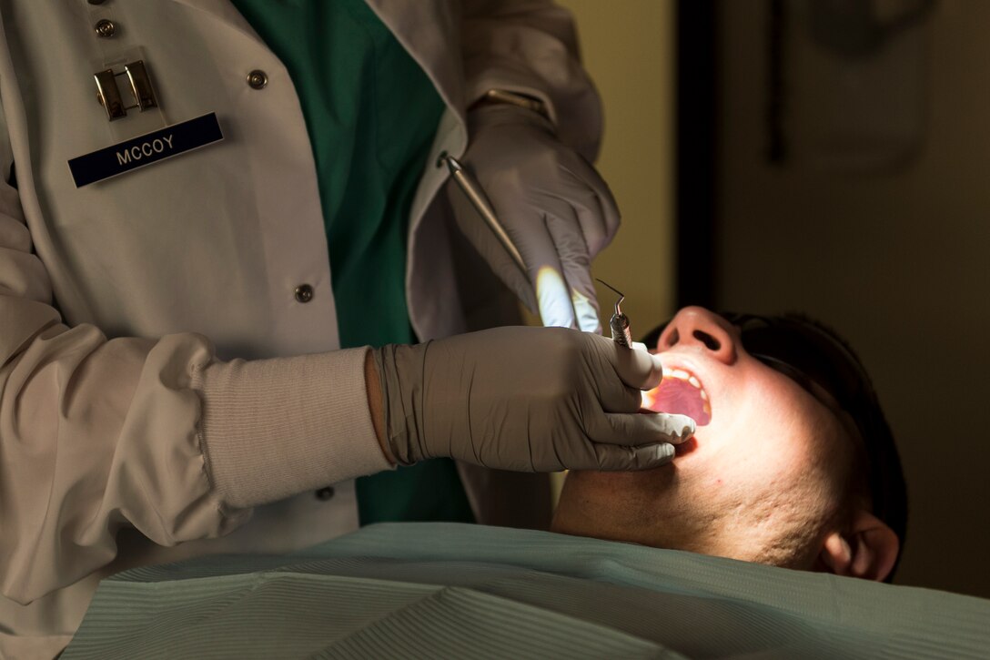 Capt. Lane McCoy, 23d Aerospace Medicine Squadron general dentist, left, performs a dental exam on Senior Airman Gabriel Jimenez, 23d Aerospace Medicine Squadron public health technician, right, during 'Deployers 1st' Thursday, April 4, 2019, at Moody Air Force Base, Ga. 'Deployers 1st' Thursdays is a program that prioritizes giving deploying Airmen medical clearance faster. (U.S. Air Force photo by Airman 1st Class Hayden Legg)