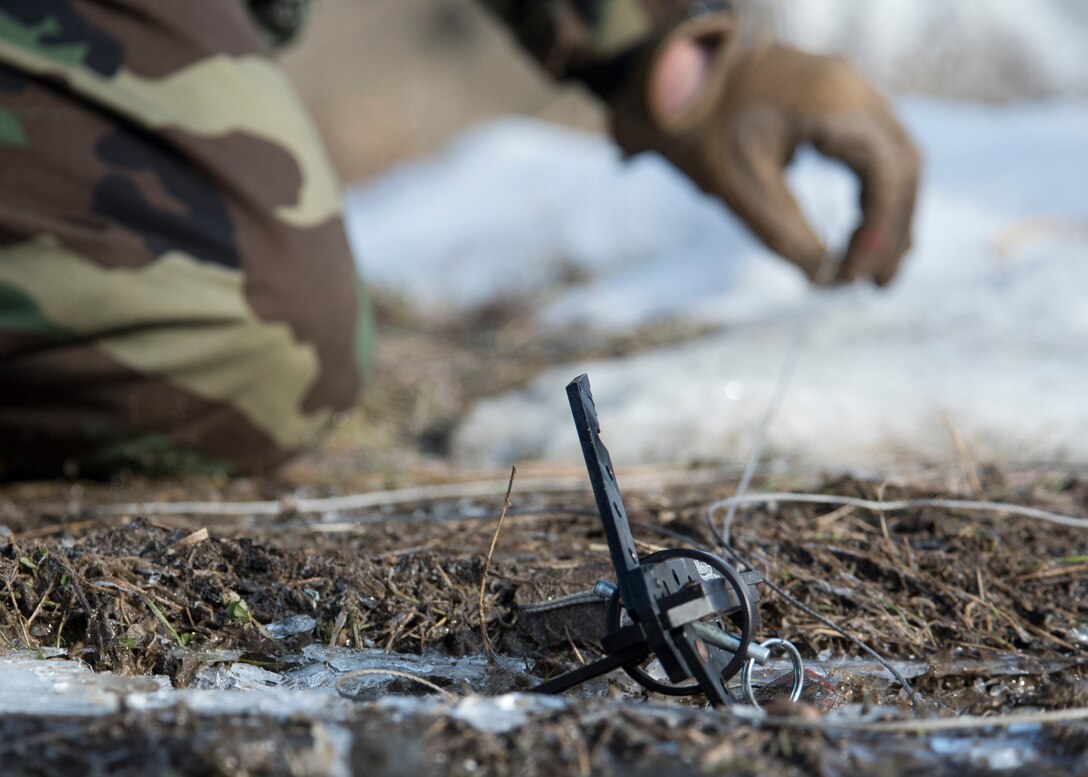 U.S. Air Force Staff Sgt. Colby Clemens, a 673d Civil Engineer Squadron Explosive Ordnance Disposal, attaches a grappling device on a remote pull to detonate simulated submunitions in a simulated chemical environment during Polar Force 19-4 at Joint Base Elmendorf-Richardson, Alaska, April 2, 2019. Polar Force is a two-week exercise designed to test JBER’s mission readiness and strengthen and develop the skills service members require when facing adverse situations.