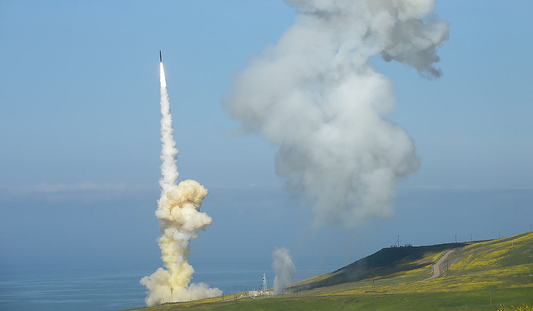 A missile launches as a cloud of smoke lingers in the sky.