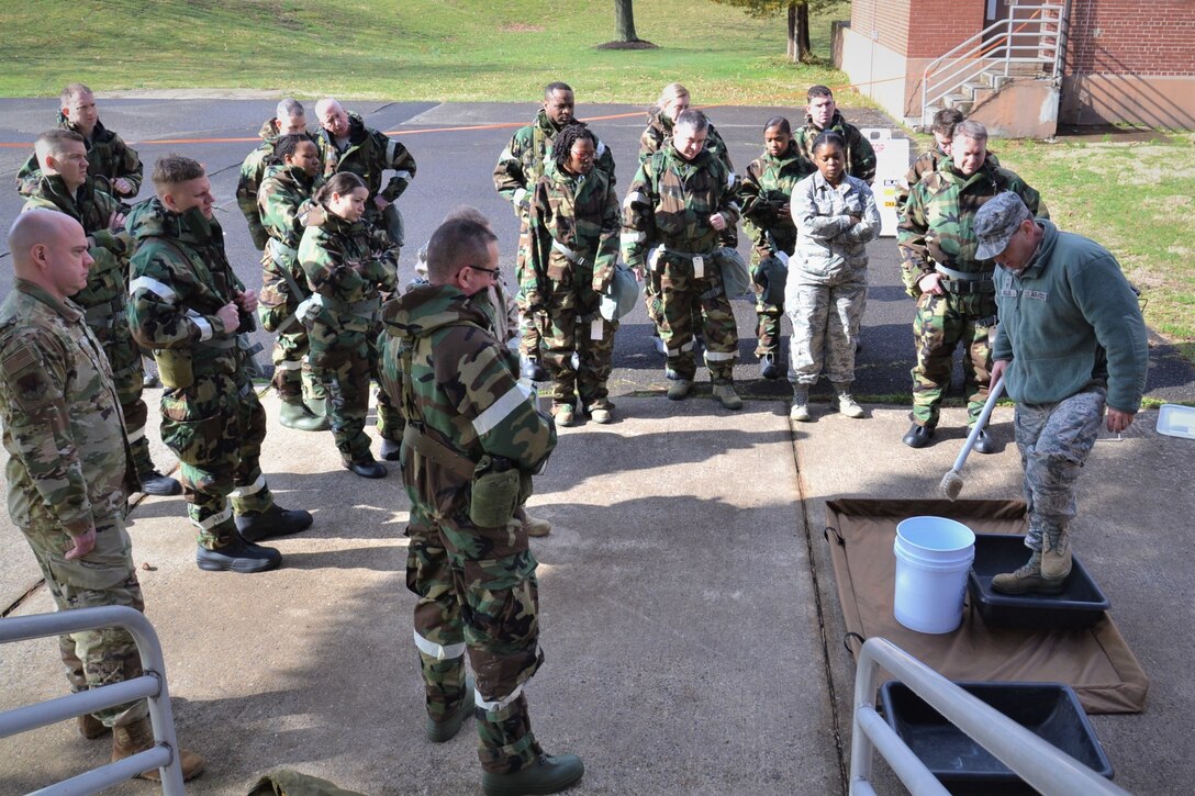 Group of ANG members in MOPP gear stand outside for instruction