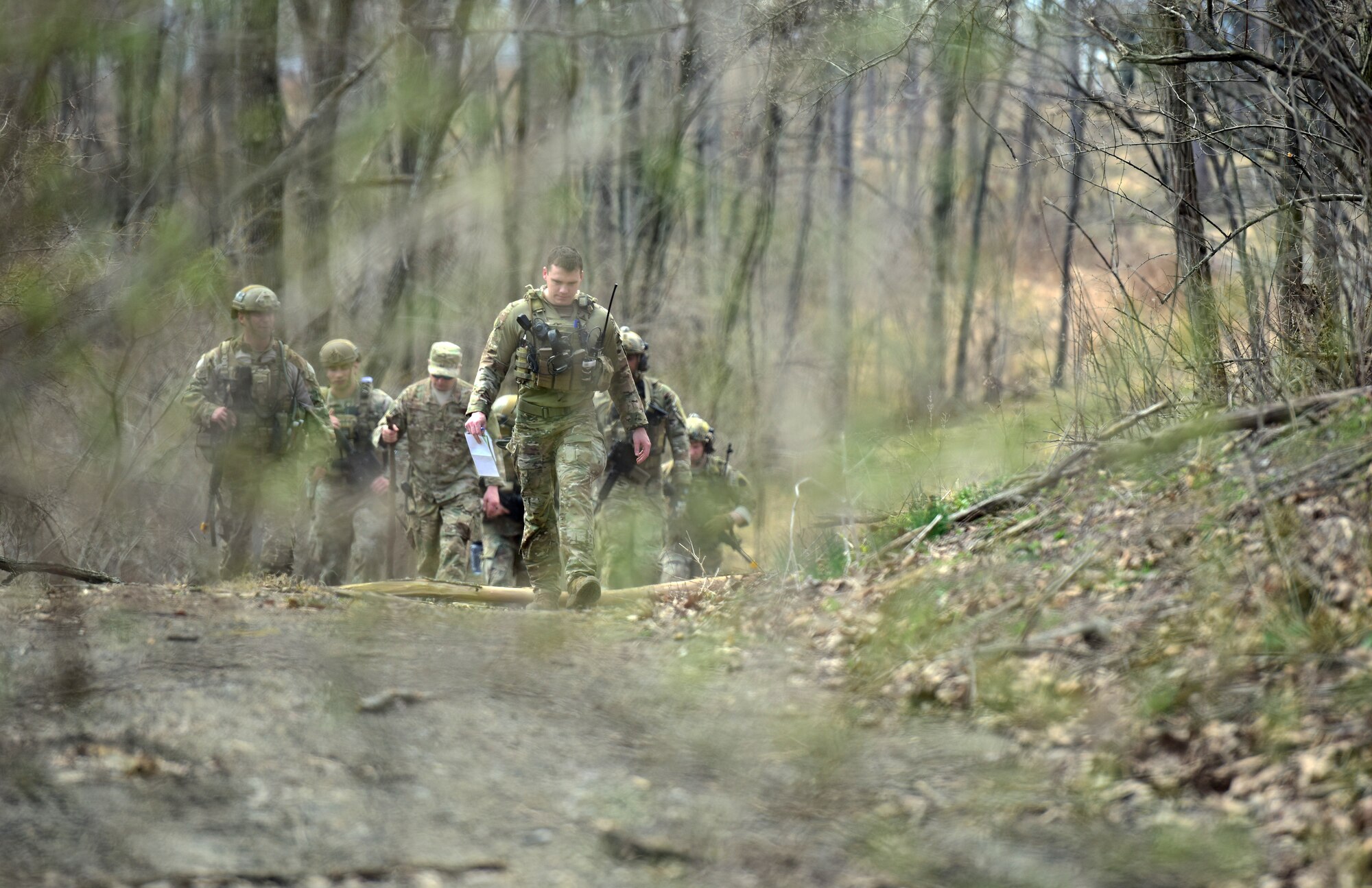 Airmen of the 148th Air Support Operations Squadron, 193rd Special Operations Wing, walk through the woods during a Tactical Combat Casualty Care field training exercise April 6, 2019, at Fort Indiantown Gap, Annville, Pennsylvania. Airmen participating in the FTX were separated into groups differentiating between being positioned with vehicles as well as on foot. (U.S. Air National Guard photo by Staff Sgt. Rachel Loftis)