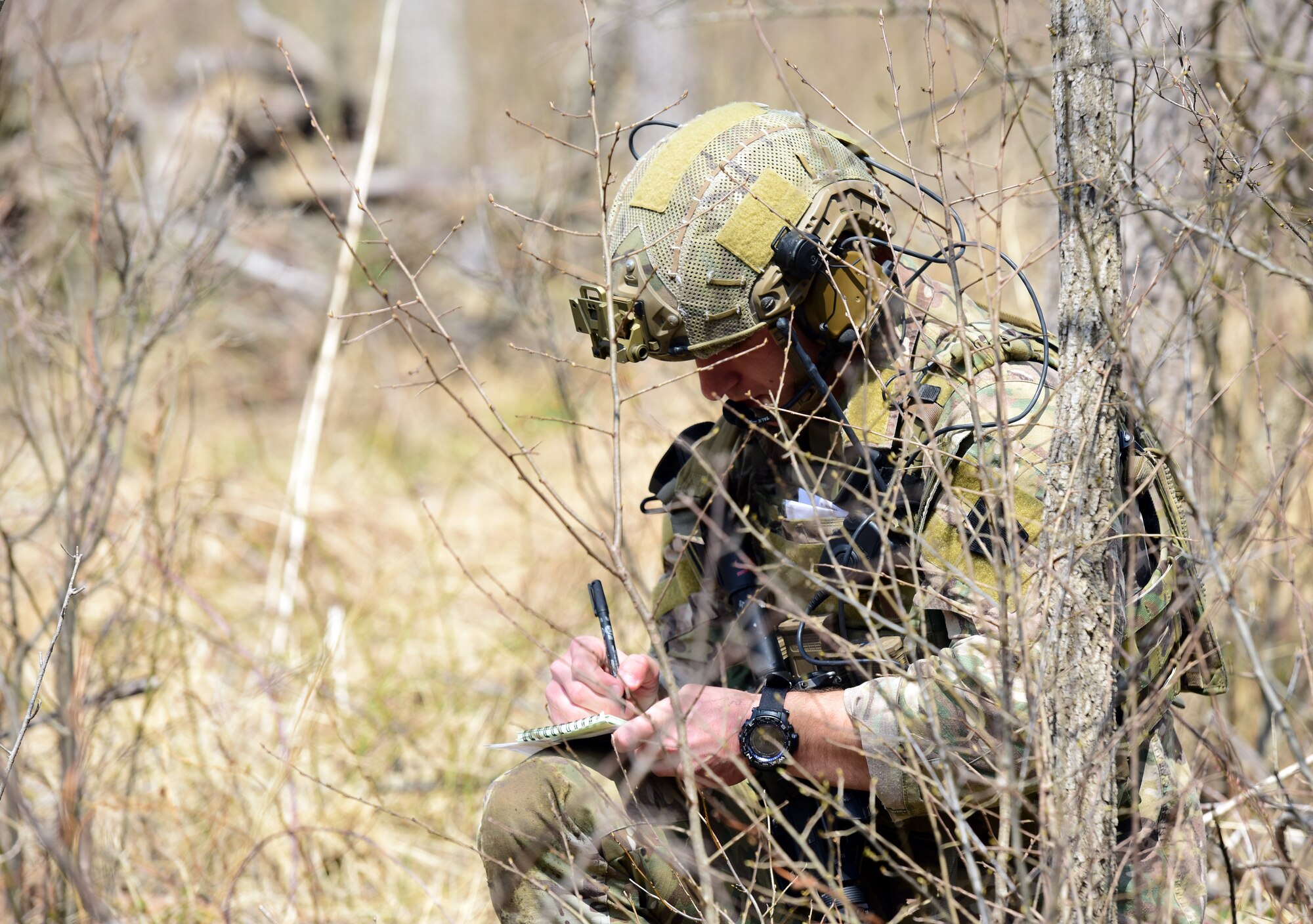 A joint terminal attack controller Airman with the 148th Air Support Operations Squadron, Fort Indiantown Gap, Annville, Pennsylvania, writes down information during a Tactical Combat Casualty Care field training exercise April 6, 2019, at the fort. The Airman maintained a low profile while relaying and receiving important information that was pertinent for the success of the FTX. (U.S. Air National Guard photo by Staff Sgt. Rachel Loftis)
