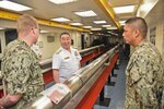 SANTA RITA, Guam (April 8, 2019) -Cmdr. Andrew Maurice, repair officer aboard the submarine tender USS Emory S. Land (AS 39) and Chief Electronics Technician Enrique Camacho lead Vice Adm. Tatsuhiko Takashima, Commander, Fleet Submarine Forces for Japanese Maritime Self-Defense Force, on a guided tour of the ship's sail shop. During his visit to Guam, Takashima viewed ships, facilities and sites on island including ship repair, quality-of-life facilities for submariners and partnership opportunities in the region.