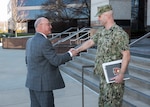 Civilian shakes hand with military in front of steps