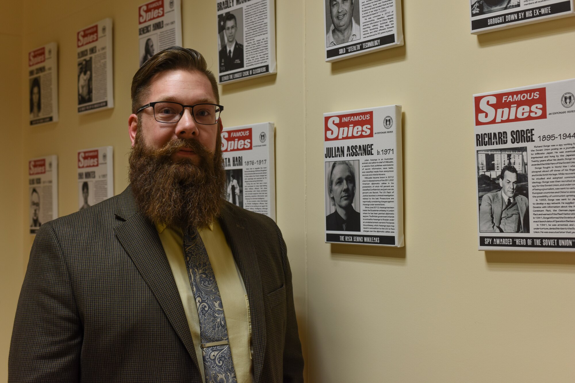 Brandon Criss, 39th Air Base Wing Chief of information protection, stands next to the wall of famous spies March 14, 2019, at Incirlik Air Base, Turkey.